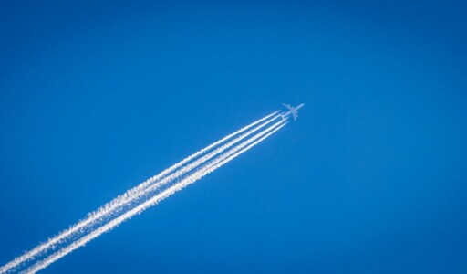Airplane flying in the blue sky with contrails behind it